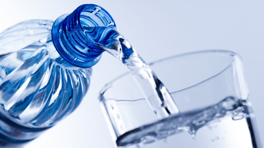 Agua vertida desde una botella hacia un vaso